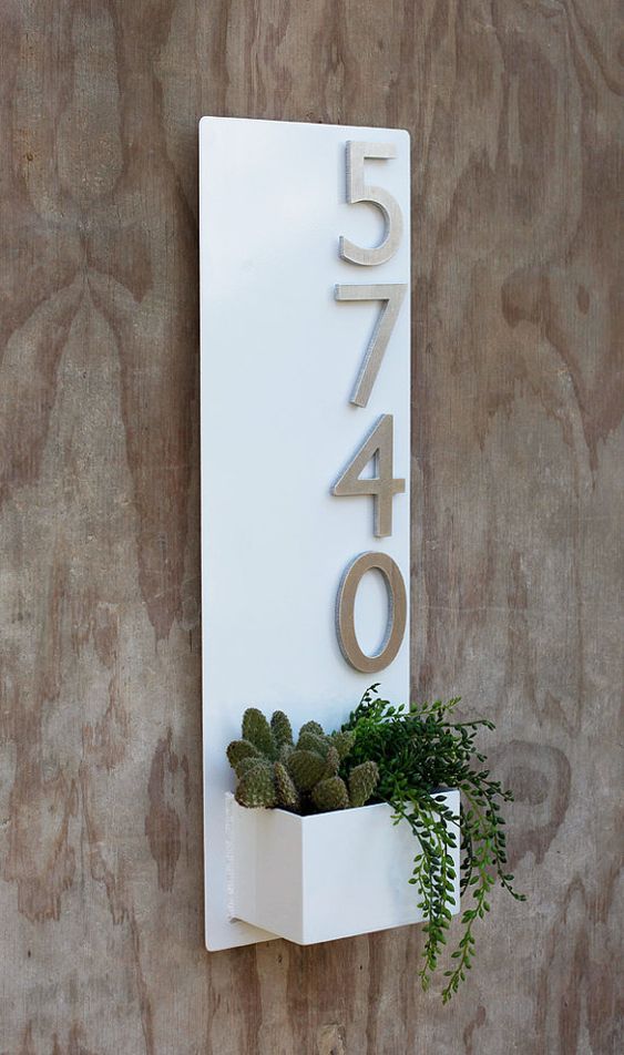 a white wall planter with aluminum numbers and cacti and succulents in the planter for a modern feel