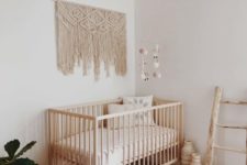 26 a boho baby’s room with a wicker lampshade, a macrame hanging, a boho rug and a ladder