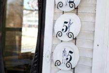 26 house numbers made up of vintage skeleton stenciled plates displayed on a hangign metal shelf attached to the wall