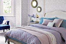 26 printed lilac wallpaper and Roman shades bring a vintage feel to the space, and lilac bedding helps with that