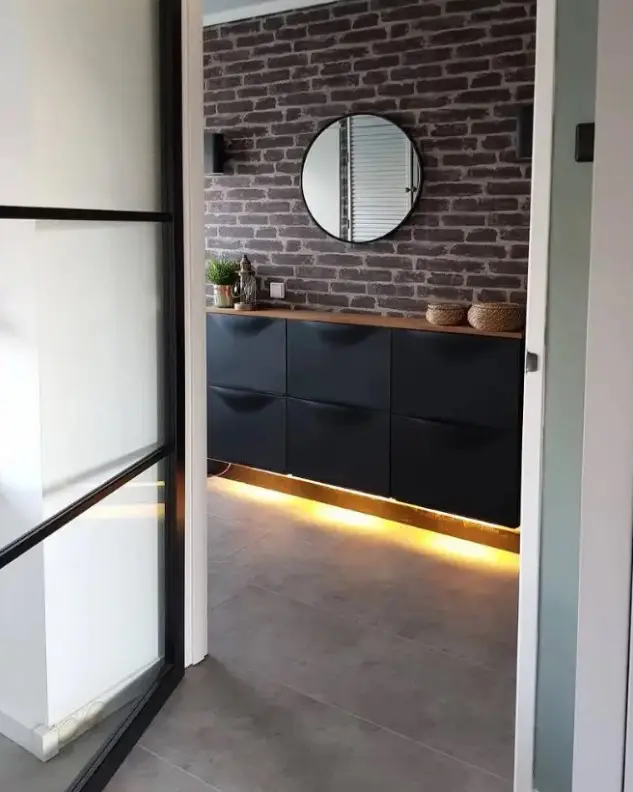 A black IKEA Trones piece attached to the wall, with a stained countertop and built in lights underneath