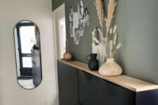 a boho entryway with a black Trones piece with a wooden counterop, a photo collage, grasses in vases and some other decor
