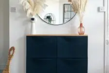 a boho entryway with a navy Trones piece and a wooden countertop, grasses and a round mirror is awesome