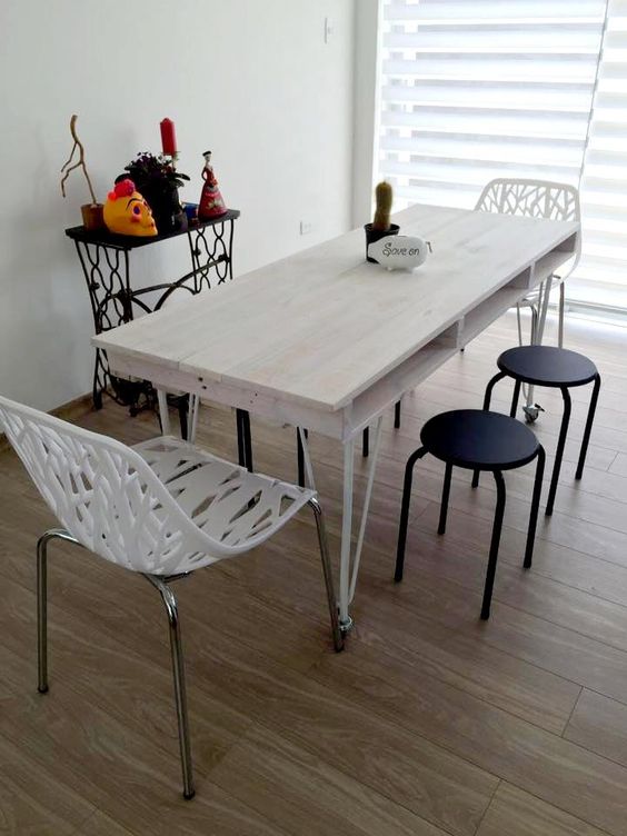 a relaxed whitewashed pallet dining table with a tabletop of a single pallet and thin metal legs on casters