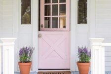 03 a blush door in farmhouse style, wall lamps and planters with purple blooms for a cozy rustic feel