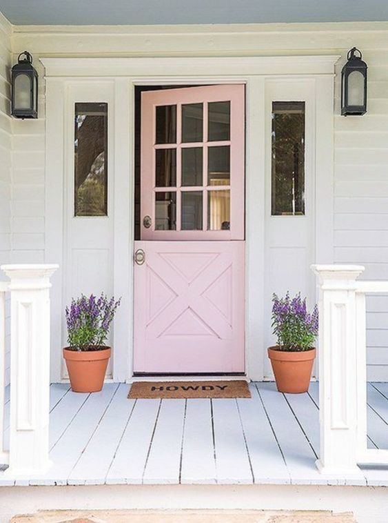 a blush door in farmhouse style, wall lamps and planters with purple blooms for a cozy rustic feel
