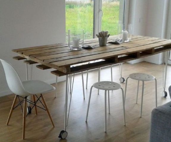 a contemporary dining table with a pallet as a tabletop and hairpin legs on casters plus modern white chairs