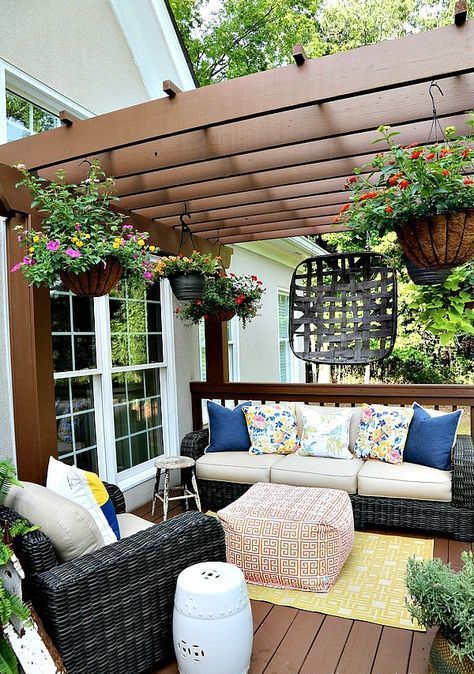 a super bright summer deck with ble, yellow and pink highlights, potted blooms hanging down and bright rugs