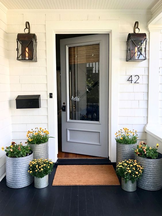 galvanized planters with the same bright blooms give a rustic and cozy feel to the porch