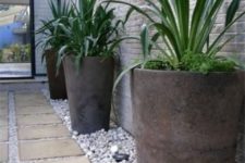 05 oversized concrete planters with the same plants placed on contrastign white pebbles is a bold idea