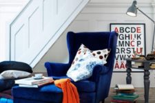 06 a navy velvet wingback chair with a matching ottoman and some colorful pillows for comfortable reading