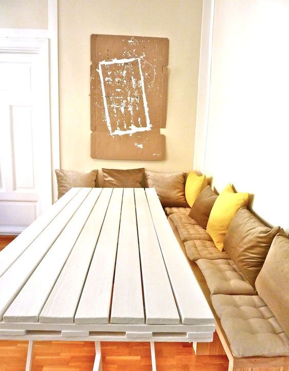 a white dining table with a tabletop made of a single pallet on thin metal legs is a bold contemporary idea