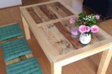 07 a light-colored stained dining table of pallet wood and matching benches with colorful cushions