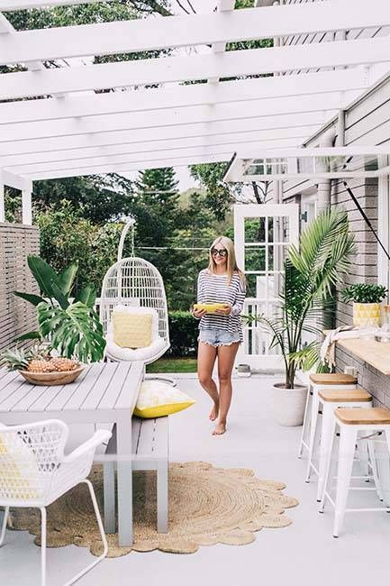 a tropical terrace with a pass through window as a bar counter and an eating space, potted plants and a rattan hanging chair for a tropical feel