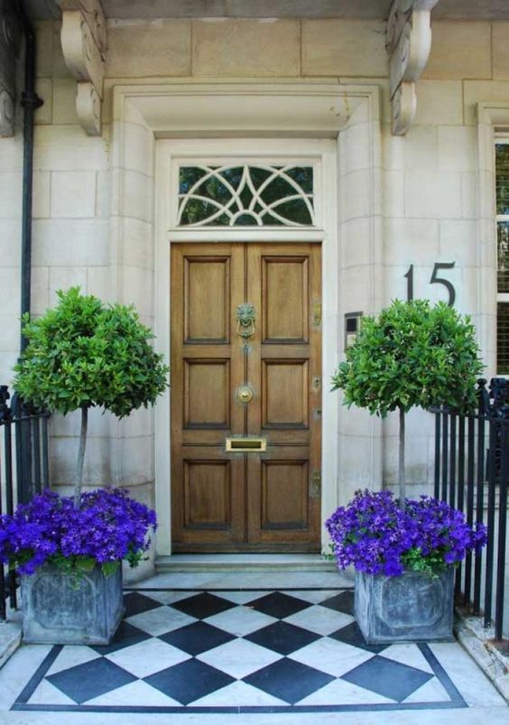 vintage box planters with bright purple blooms and trees plus a neutral wooden door