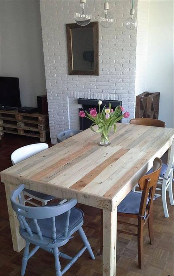a neutral dining table of stained pallet wood and mismatching chairs for an eclectic dining space