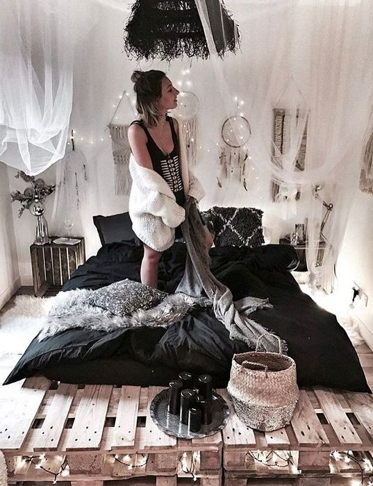 a pallet bed with lights inside and over it for a boho chic bedroom, a tulle canopy over the bed makes it cooler