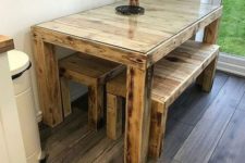 09 a rustic dining table with a pallet wood table with a glass tabletop and matching benches all stained in a light shade