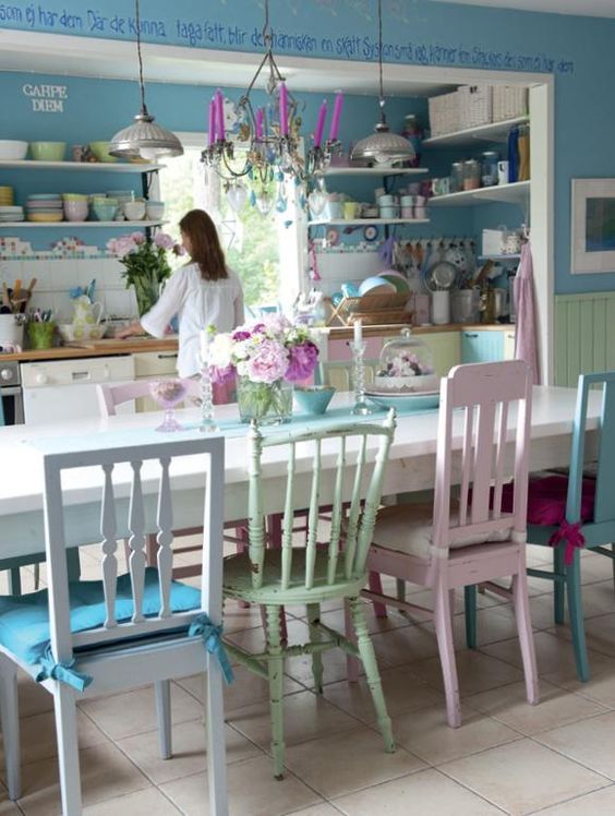 mismatching pastel chairs with colorful cushions for a colorful and eclectic dining space