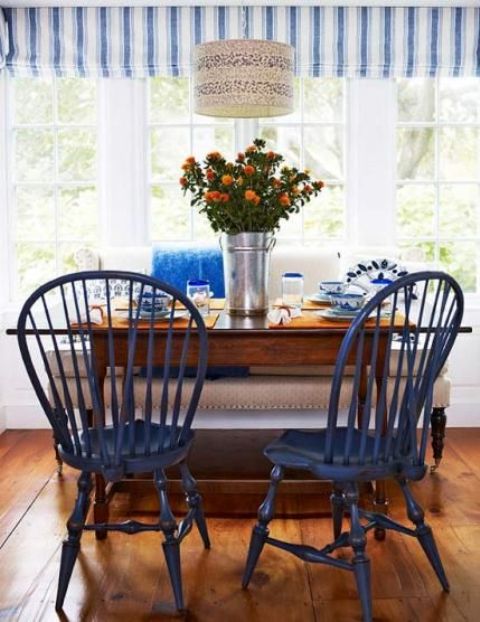 A beach inspired dining space with navy chairs and touches of bold blue plus a printed lampshade