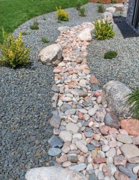 a dry creek bed of colorful pebbles and with smaller pebbles plus some shrubs