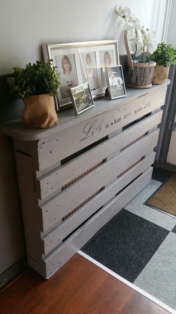 a whitewashed pallet console table doesn't only give a tabletop for storage but also hides a radiator