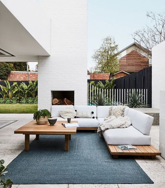 an outdoor living room with a fireplace and comfy furniture of pallets plus a cool blue rug