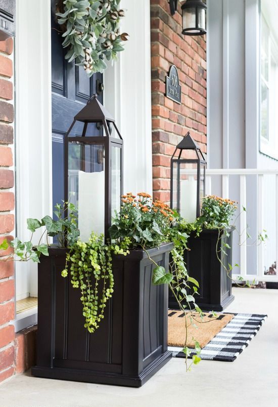symmetrical black wooden planter boxes with greenery, blooms and large candle lanterns for farmhouse charm