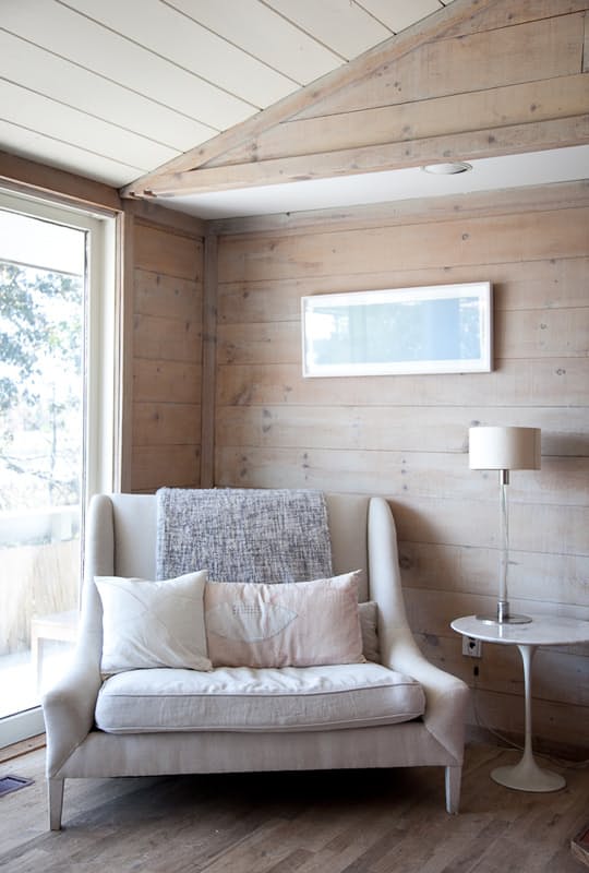 a comfy oversized neutral chair with cushions and pillows placed by the window to read cozily
