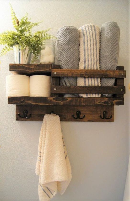 a rustic stained pallet shelf for a small bathroom features toilet paper storage, towel storage and even hooks for towels