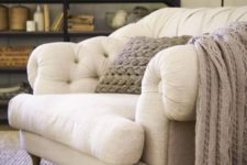 12 a gorgeous large overstuffed chair in cream, with wooden legs and a knit blanket and pillow to sink in