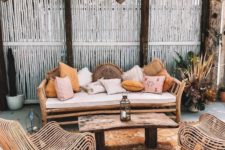 13 a boho tropical patio with a wooden bench and lots of pillows, catchy rattan chairs, a wooden table and a boho rug plus Moroccan lanterns