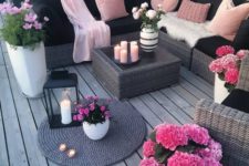 13 a bright black and blush deck with wicker furniture, blush pillows and hot pink potted blooms