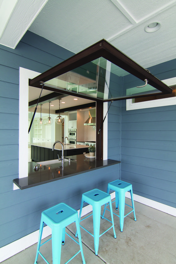 a garage-style dark framed window, a black tabletop and bright blue metal stools for cofy meals