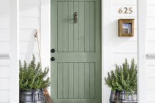 14 a sage green door matches the greenery that is growing in the large milk churns