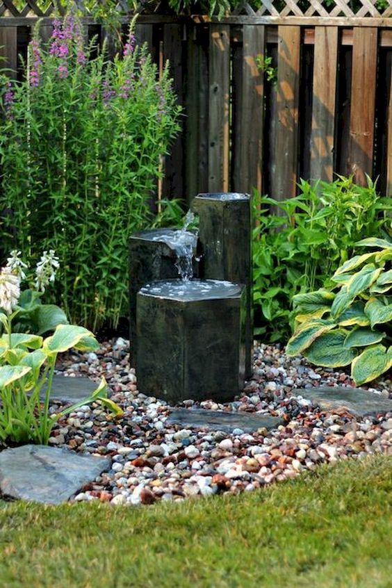 stylish black rock fountains with pebbles around will make your front yard more chic and bold