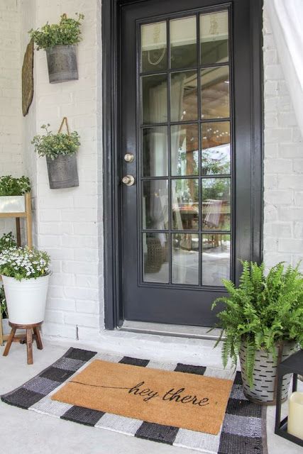 a black glass door, a buffalo plaid rug, a metal planter with fern and some planters on the wall