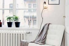 17 a comfortable contemporary chair of metal and white leather and a blanket for cozy reading