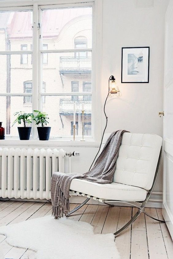 a comfortable contemporary chair of metal and white leather and a blanket for cozy reading