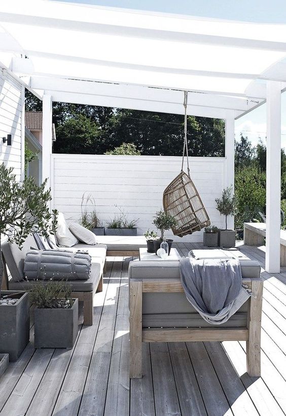 a welcoming summer lounge with comfortable wooden furniture and touches of concrete plus a rattan chair