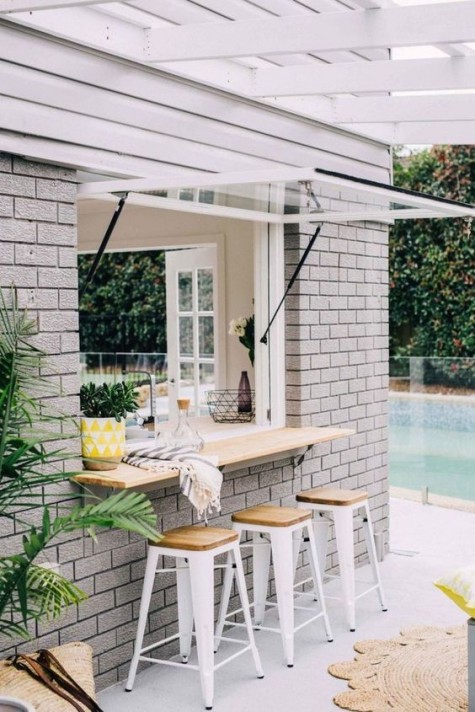 A garage door styled window and an outdoor breakfast space or bar top withh white metal chairs and wooden tops