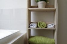 19 a bathroom shelving unit with several tiers for storign towels and some potted greenery built of pallets