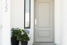 19 a dove grey door, a vintage lamp and a duo of black planters with blue flowers create a cozy vintage-inspired porch