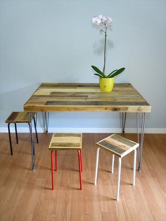 a rustic dining table with a pallet wood tabletop on hairpin legs and some matching stools