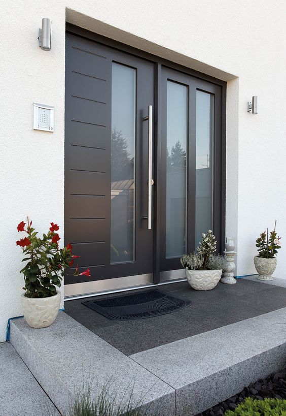 a large contemporary door with glass inserts, three planters with blooms and greenery on the porch