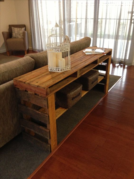 A rich stained pallet console table with an additional shelf is a great piece to place behind your sofa