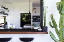 20 a sliding black framed window and a dark stained tabletop with cacti, black metal stools for a chic look