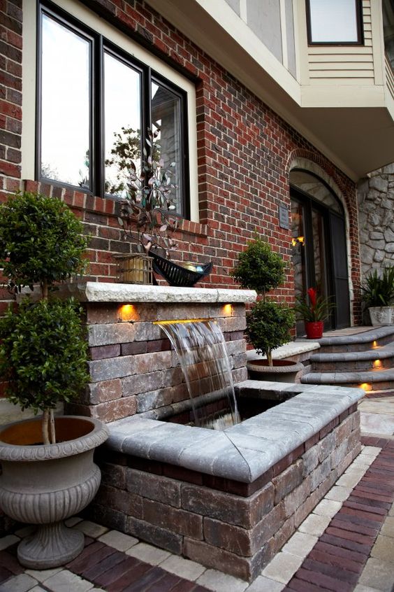 a water feature clad with brick and some additional lights is an elegant and stylish idea for a front yard