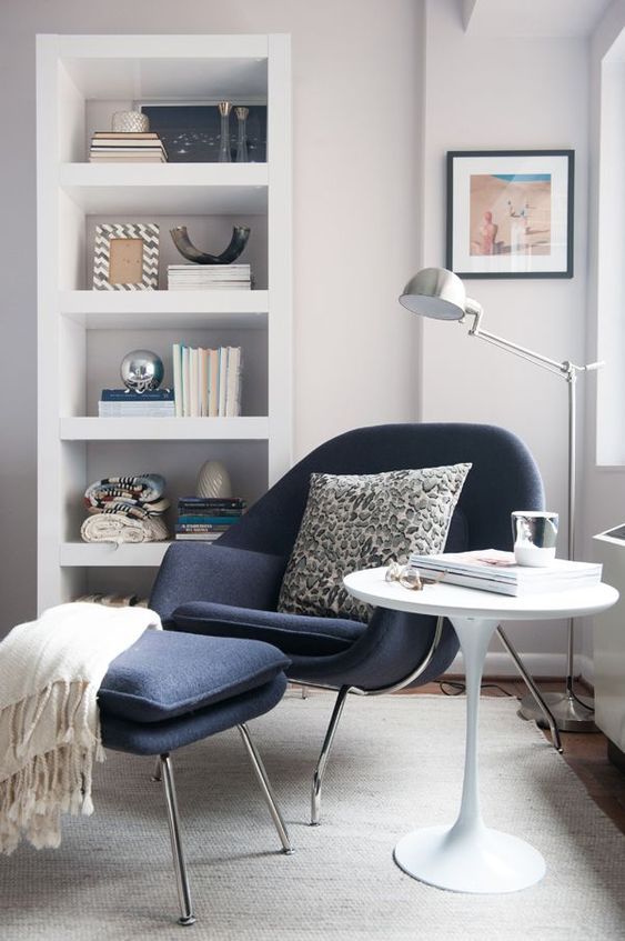 A navy chair and a footrest on tall metal legs inspired by mid century modern designs