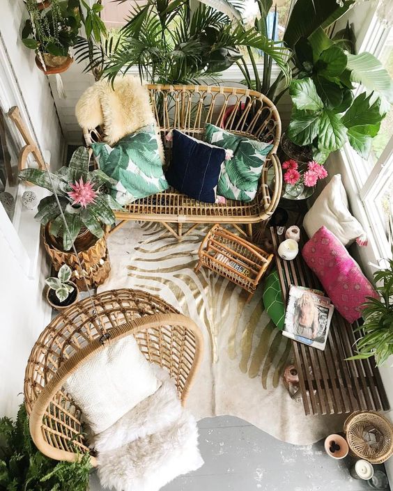 a tropical balcony with rattan furniture, potted torpical plants, colorful pillows and a zebra print rug